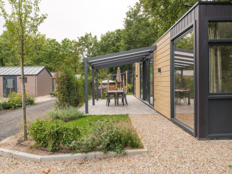 Moderne Lodge mit Holzfassade, überdachter Terrasse und Garten im Veluwepark de Bosgraaf in den Niederlanden.