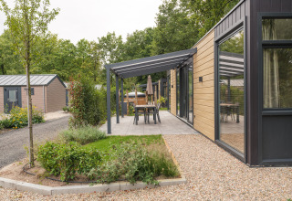 Moderne lodge met houten gevel en overdekt terras in Veluwepark de Bosgraaf, Nederland.