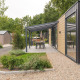 Lodge moderne avec façade en bois, terrasse couverte et salle à manger au Veluwepark de Bosgraaf, Pays-Bas.