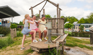 Trois enfants jouent avec une pompe à eau sur l’aire de jeux de Vakantiepark Ackersate à Gelderland.