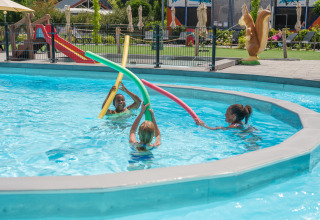 Kinder spielen mit bunten Poolnudeln im Schwimmbad des Vakantiepark Ackersate, Gelderland, Niederlande.
