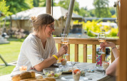 Due donne si godono vino e cibo sulla terrazza di una tenda safari al Vakantiepark Ackersate, Paesi Bassi.
