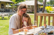 Mamma e figlia gustano un dessert insieme all’aperto al Villatent Nomad presso Vakantiepark Ackersate, Olanda.