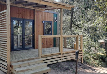 Standaard Mobilhome 23m2 with wooden deck, modern exterior, and surrounded by trees in a natural setting.