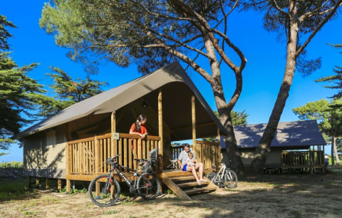 Gezin geniet voor een comfortabele lodge tent bij Flower Camping Monplaisir in Frankrijk, met fietsen.