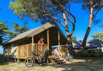 Familie slapper af på verandaen af en komfortabel safaritelt ved Flower Camping Monplaisir i Frankrig.