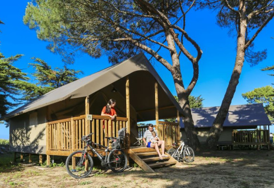 Gezin geniet voor een comfortabele lodge tent bij Flower Camping Monplaisir in Frankrijk, met fietsen.