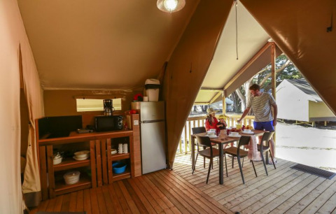 Interieur van een safaritent op Flower Camping Monplaisir in Frankrijk, familie eet buiten samen.