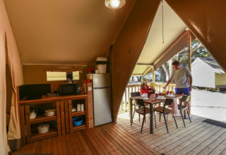 Interieur van een safaritent op Flower Camping Monplaisir in Frankrijk, familie eet buiten samen.
