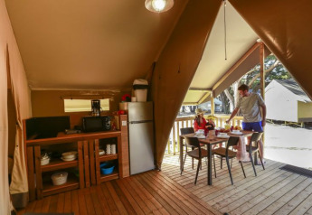 Interieur van een safaritent op Flower Camping Monplaisir in Frankrijk, familie eet buiten samen.