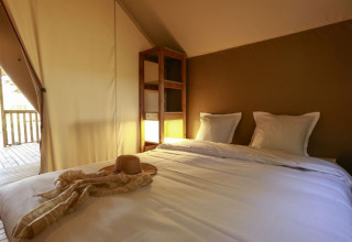 Binnenaanzicht van een comfortabele safaritent met tweepersoonsbed bij Flower Camping Monplaisir in Frankrijk.