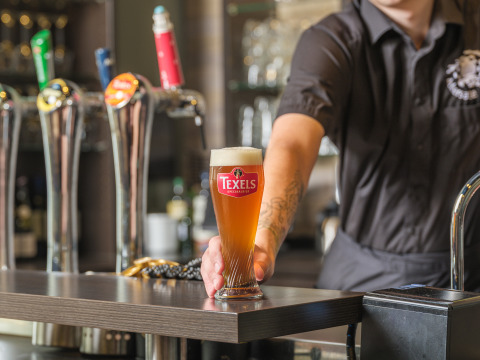 Un camarero sirve un vaso de cerveza Texels en el bar del Vakantiepark Ackersate en Gelderland, Países Bajos.