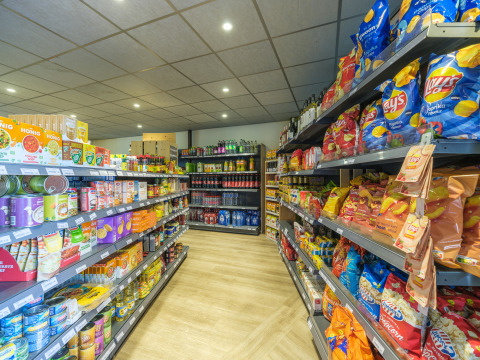 Estantes llenos de snacks, conservas y bebidas en el supermercado de Vakantiepark Ackersate, Gelderland, Países Bajos.