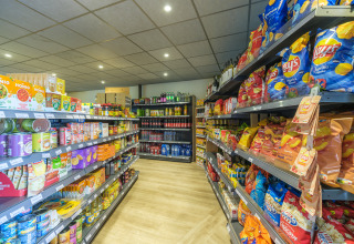 Hylder fyldt med snackposer, konserves og drikkevarer i supermarkedet på Vakantiepark Ackersate, Gelderland.