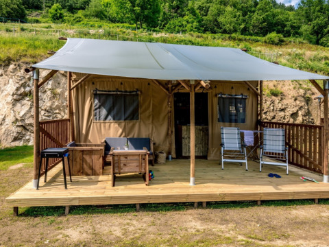 Tienda safari Lodgetent con instalaciones sanitarias en Camping l'Ardechois, Francia, con terraza y muebles