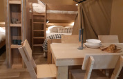 Innenraum eines Safarizelts auf Camping Le Bois de la Gachère in Frankreich mit Esstisch und Etagenbetten.