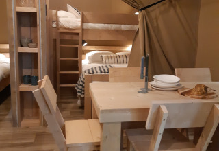 Indretning af en safari-telt i Camping Le Bois de la Gachère, Frankrig, med spisebord og køjesenge.