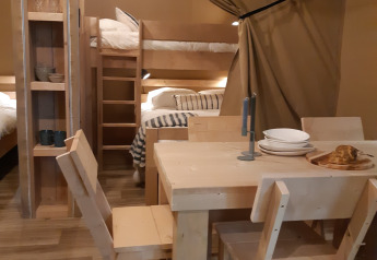 Indretning af en safari-telt i Camping Le Bois de la Gachère, Frankrig, med spisebord og køjesenge.