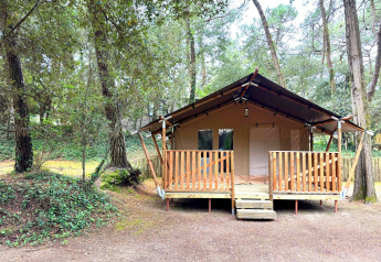 Tenda safari con veranda in legno immersa nella foresta al Camping Le Bois de la Gachère in Francia.