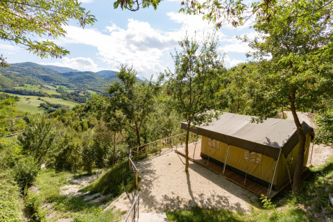 Safari tent with private sanitary facilities at Camping Il Collaccio in Italy, overlooking green hills.