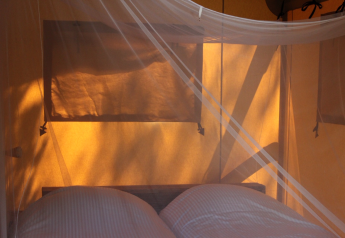 Interno di una tenda safari con letto matrimoniale e zanzariera al Camping Il Collaccio in Italia.
