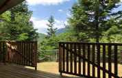 Vista da una tenda safari al Camping Il Collaccio, Italia, con terrazza in legno e natura rigogliosa.