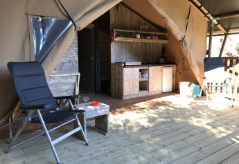 Interior de tienda safari con instalaciones sanitarias en Camping Les Lauriers Roses, Francia, terraza de madera.