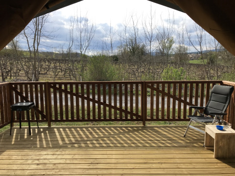 Uitzicht vanaf een safaritentveranda met stoel, tafel en barbecue bij Camping Saint Amand in Frankrijk.