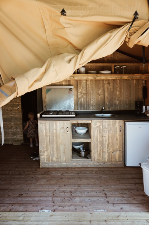 Vista interior de tienda safari con cocina y sanitarios en Camping Saint Amand en Francia.