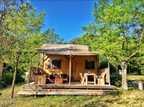 Safari Lodge-telt på Campsite Monti del Sole, Italien, omgivet af træer og solskin, afslappende udendørs.