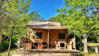 Safari Lodge-tent op Camping Monti del Sole in Italië, tussen groen en zonlicht in een natuurgebied.