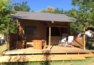 Safari Lodge tent met houten terras en stoelen op Camping Monti del Sole, Italië, omgeven door groen.
