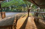 Veranda in legno con arredi esterni presso una tenda safari al campeggio Monti del Sole in Italia, alba.