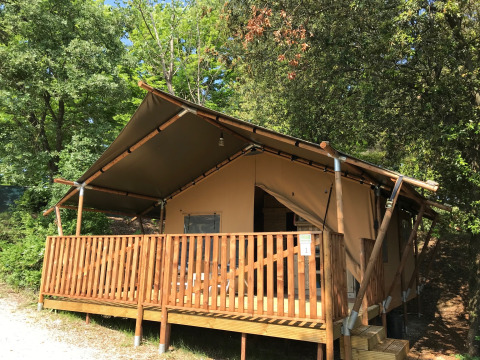 Tente safari au camping Mar y Sierra en Italie, avec terrasse en bois entourée de verdure.