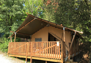 Safari-telt på Campsite Mar y Sierra i Italien med træveranda, omkranset af træer og natur.