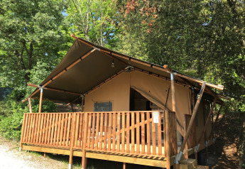 Safari-Zelt auf dem Campingplatz Mar y Sierra in Italien mit Holzterrasse, umgeben von Bäumen.