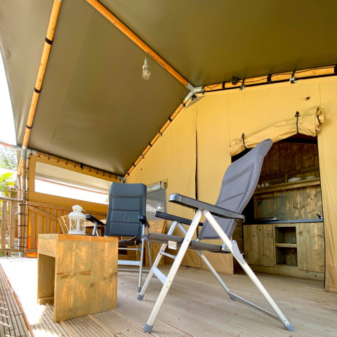 Knusse zithoek bij safaritent op Camping Mar y Sierra in Italië, met stoelen en houten tafeltje.