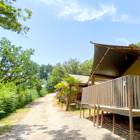Tente safari au camping Mar y Sierra en Italie, avec terrasse en bois et entourée de verdure.