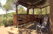 Safaritent Lodgetent met sanitaire voorzieningen op Camping Paradiso, Italië, met houten terras en stoelen.