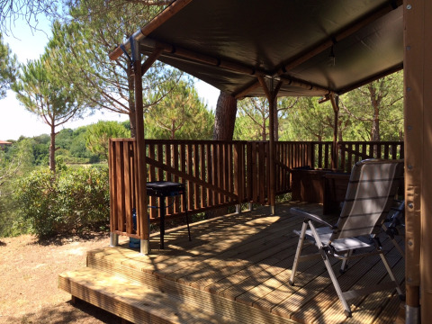 Safaritent Lodgetent met sanitaire voorzieningen op Camping Paradiso, Italië, met houten terras en stoelen.