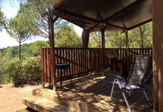 Safaritent Lodgetent met sanitaire voorzieningen op Camping Paradiso, Italië, met houten terras en stoelen.