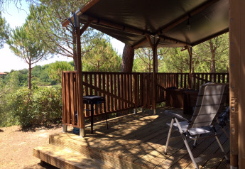 Safaritent Lodgetent met sanitaire voorzieningen op Camping Paradiso, Italië, met houten terras en stoelen.