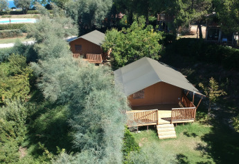 Vista exterior de tiendas safari con instalaciones sanitarias rodeadas de vegetación en Camping Paradiso, Italia.