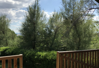 Vista desde una tienda safari con instalaciones sanitarias en Camping Paradiso, Italia, con árboles.