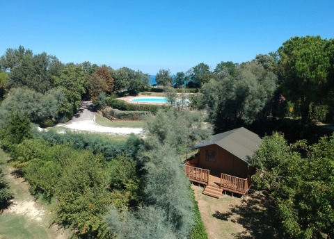 Luftfoto af safari-telt med eget bad på Camping Paradiso i Italien, omgivet af grønt og pool i baggrunden.