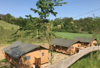 Tentes safari avec sanitaires privés à l’Agriturismo Le Sorgive e Le Volpi en Italie, entourées de verdure.