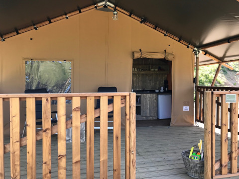 Tente safari avec terrasse en bois, coin cuisine et panier à jouets à l’Agriturismo Le Sorgive e Le Volpi en Italie.