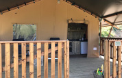 Tenda safari con veranda in legno, angolo cottura e cesta giochi ad Agriturismo Le Sorgive e Le Volpi, Italia.