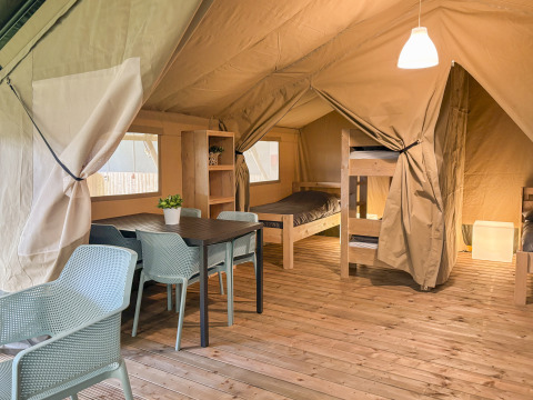 Interno di una tenda safari all'Hvalpsund Familie Camping in Danimarca con letti a castello e tavolo.