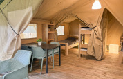Interior of a safari tent at Hvalpsund Familie Camping in Denmark with bunk beds and dining table.